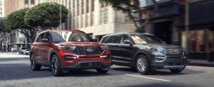 A red 2020 Ford Explorer ST and a silver 2020 Ford Explorer Hybrid driving on a street in San Antonio, TX