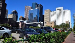 New and used cars in a parking lot with buildings in the background near San Antonio, TX